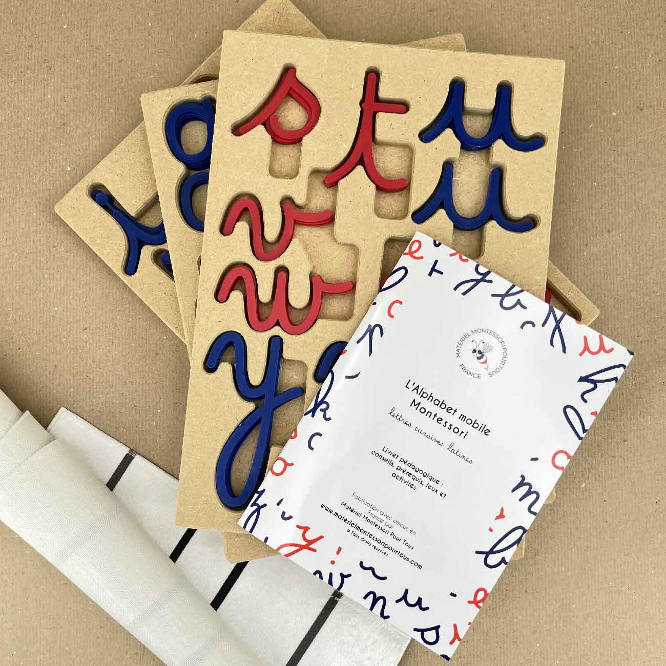 Les trois outils dédiés à l'apprentissage de l'écriture et de la lecture : le livret pédagogique pour vous accompagner dans l'utilisation de l'alphabet mobile cursif, le tapis d'écriture en velours frappé, épais et robuste pour développer l'autonomie des enfants et biensûr, notre ensemble alphabet mobile Montessori et plateaux de rangement "Montessori Tidy".